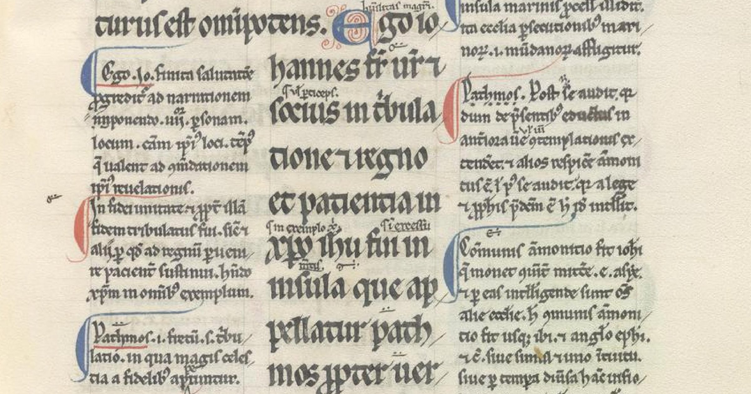 A thirteenth-century manuscript page from the Book of Revelation: a central column of large Latin script with smaller gloss written in columns on either side and between the lines, with red and blue initials.